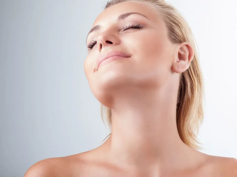 Mujer con el cuello estirado mostrando la piel del cuello y el escote