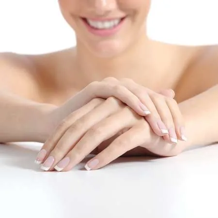 Mujer sonriente mostrando sus manos rejuvenecidas