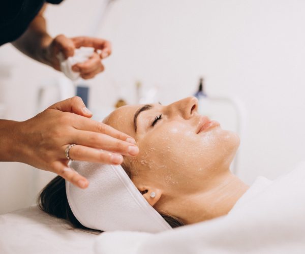 cosmetologa-limpiando-la-cara-de-una-mujer-en-un-salon-de-belleza-min