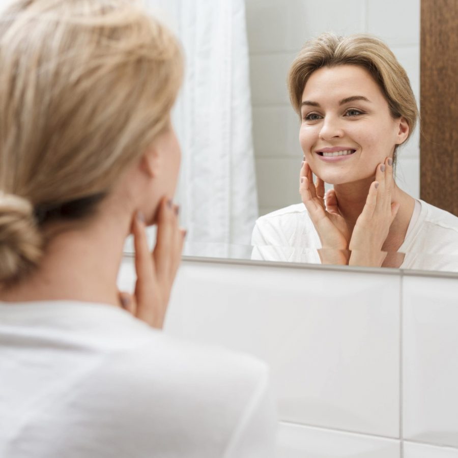 mujer-sonriente-mirando-en-el-espejo-min