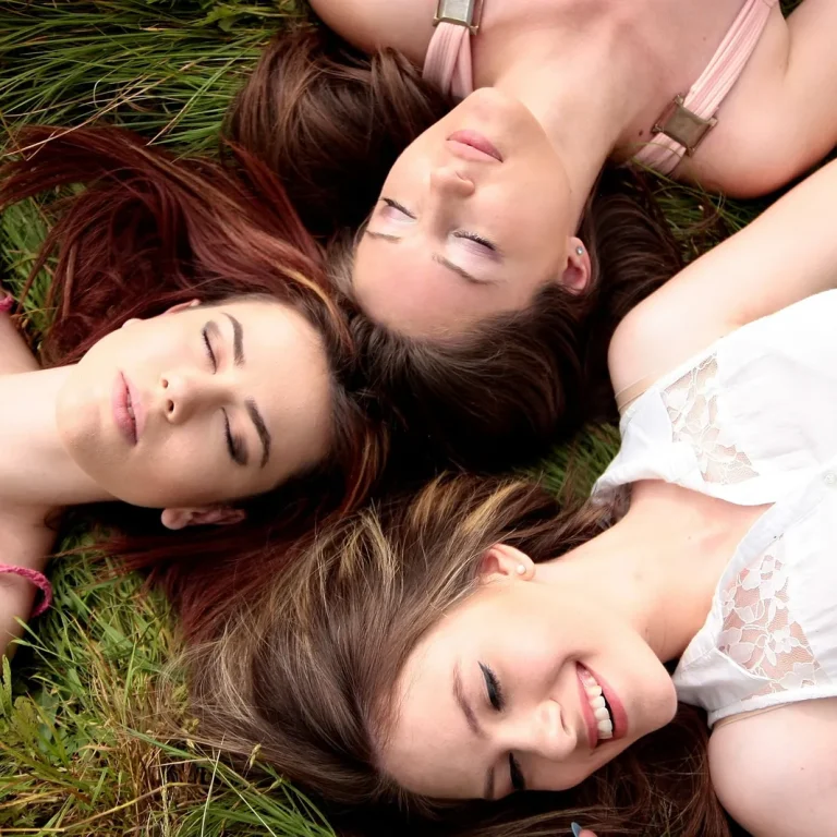 Tres mujeres sonrientes tumbadas en la hierba