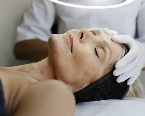 vista-recortada-del-especialista-desconocido-que-masajea-la-cara-de-una-paciente-mayor-min