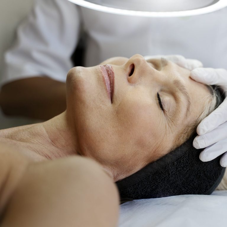 vista-recortada-del-especialista-desconocido-que-masajea-la-cara-de-una-paciente-mayor-min